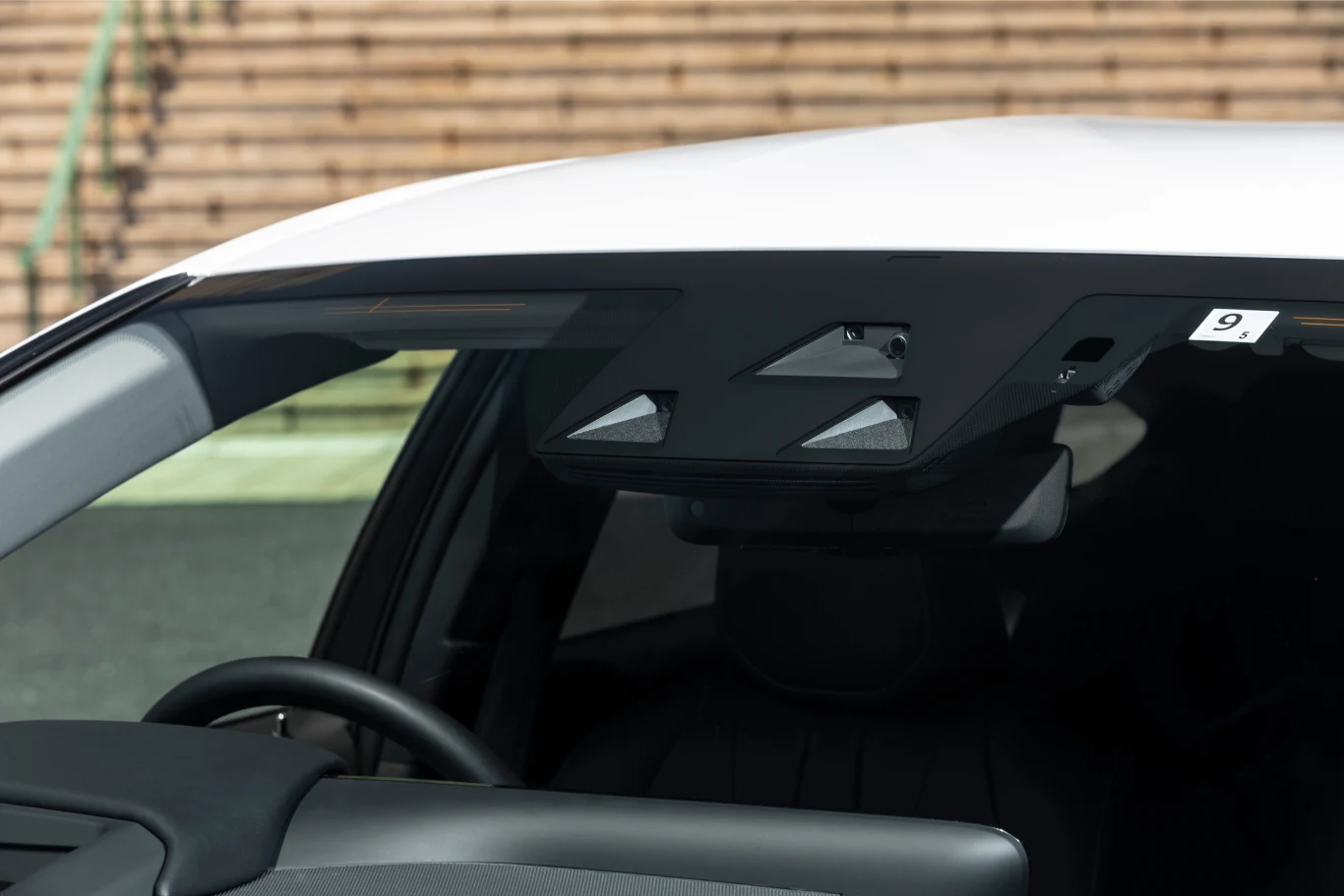 Widoczny fragment samochodu od strony przedniej szyby z zamontowaną kamerą oraz czujnikami systemów bezpieczeństwa i asysty kierowcy.