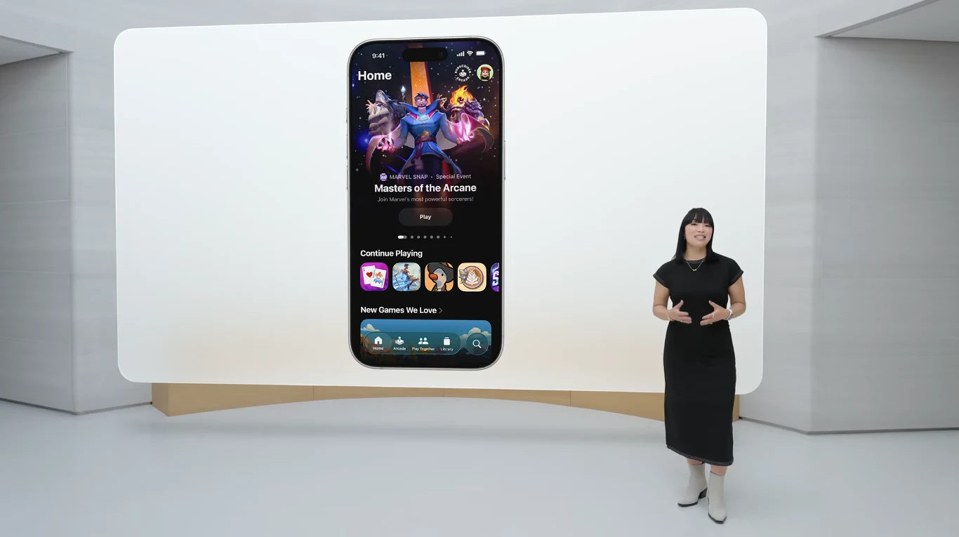 Duży ekran prezentuje interfejs aplikacji na smartfonie z grą Masters of the Arcane, przed ekranem stoi kobieta w czarnej sukience wygłaszająca prezentację.