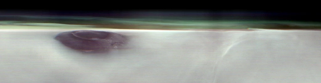 THEMIS na pokładzie sondy 2001 Mars Odyssey bada atmosferę i szuka wody pod powierzchnią Marsa ciemna, okrągła formacja na białej, gładkiej powierzchni z delikatnym, rozmytym tłem i nieregularną linią oddzielającą dwa obszary kolorystyczne