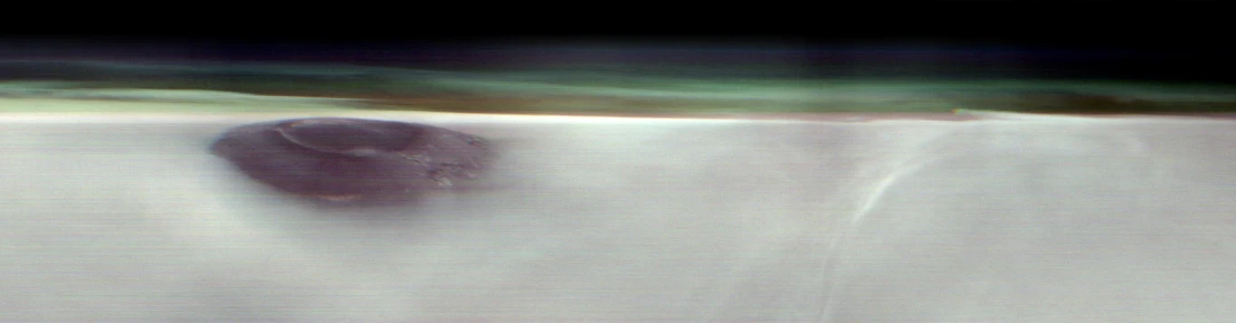 THEMIS na pokładzie sondy 2001 Mars Odyssey bada atmosferę i szuka wody pod powierzchnią Marsa ciemna, okrągła formacja na białej, gładkiej powierzchni z delikatnym, rozmytym tłem i nieregularną linią oddzielającą dwa obszary kolorystyczne