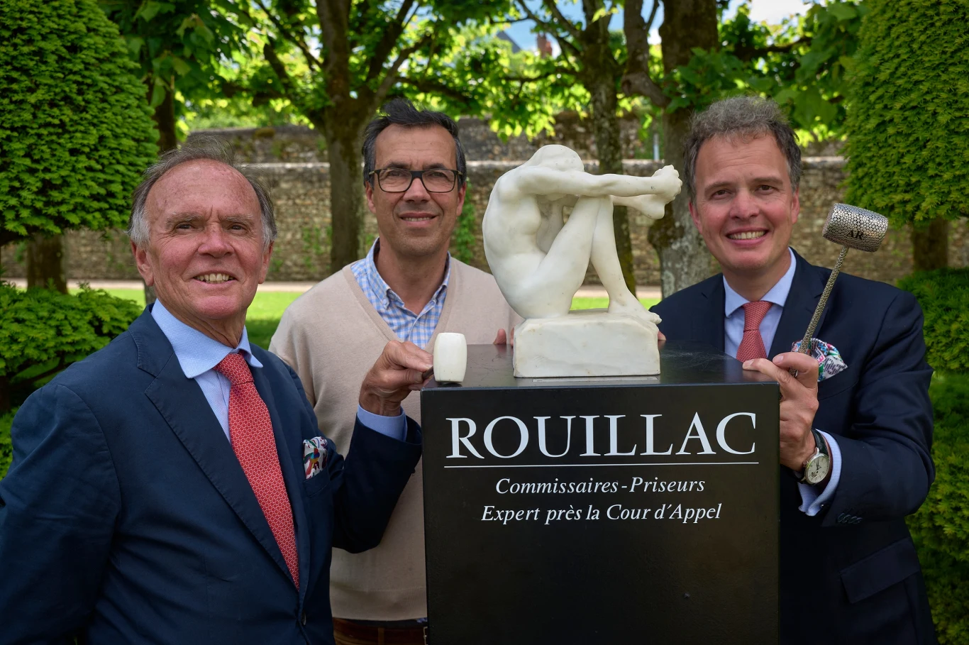 Niepozorna rzeźba uważana za kopię okazała się być oryginałem stworzonym przez słynnego artystę, Auguste’a Rodina. Trzech mężczyzn w garniturach pozuje na zewnątrz, obok cokołu z rzeźbą i napisem Rouillac Commissaires-Priseurs Expert près la Cour d'Appel. Dwóch mężczyzn trzyma w dłoniach młotek aukcyjny i kieliszek, a trzeci uśmiecha się do kamery. W tle widać ziel...