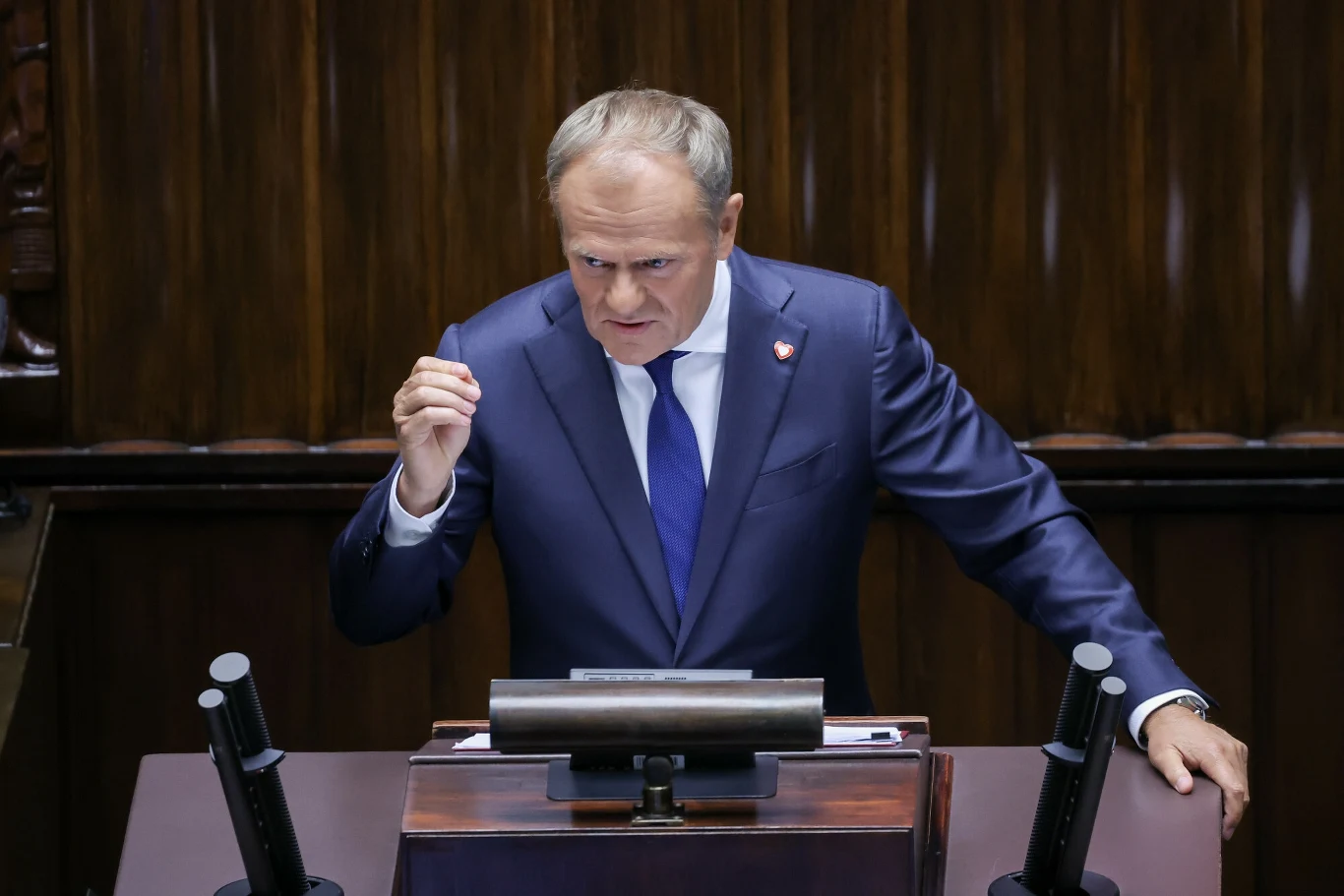 Donald Tusk zabrał głos w sprawie kontroli na granicach polsko-niemieckich Polityk w garniturze i krawacie wygłaszający przemówienie przy mównicy sejmowej, wyrażający silne emocje gestem zaciśniętej pięści, w tle drewniane panele sali obrad.