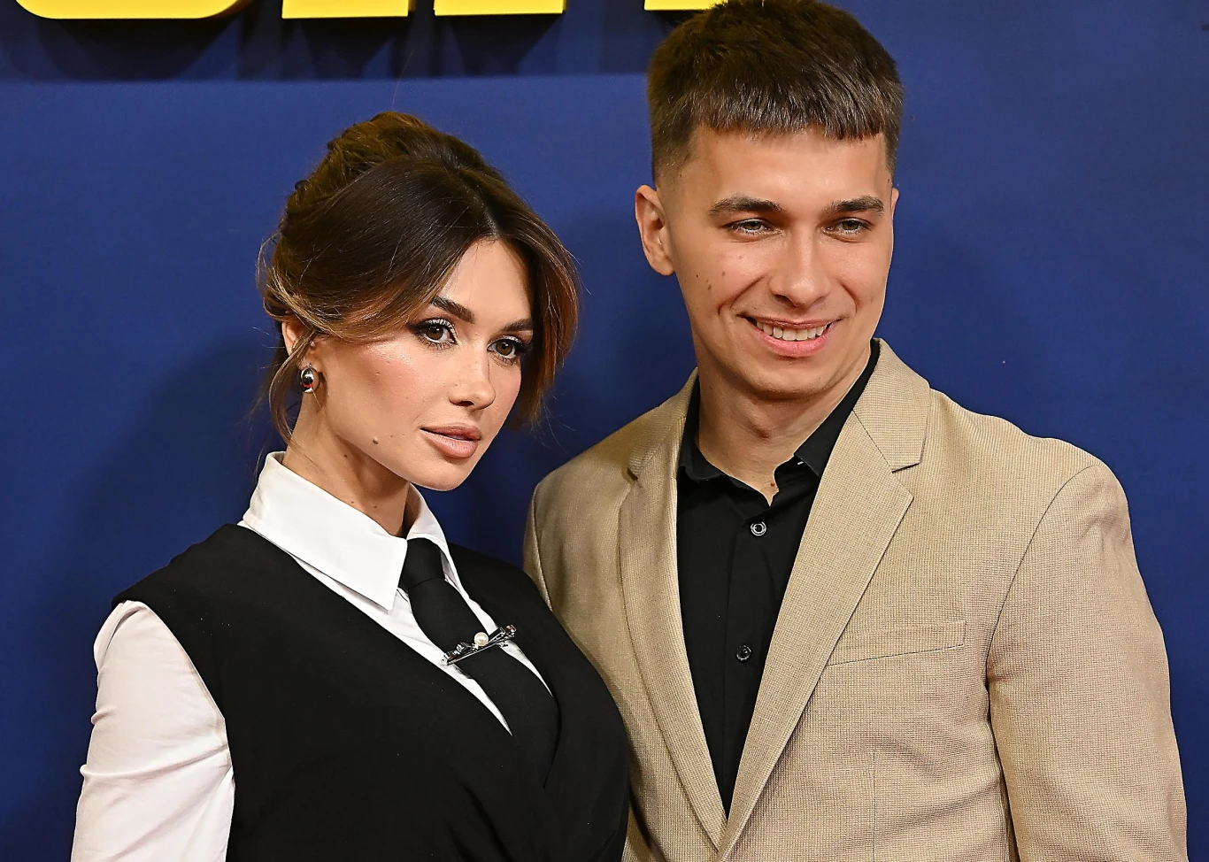 Wersow i Friz pojawią się na Ekipa Festiwalu Elegancko ubrana kobieta z upiętymi włosami oraz mężczyzna w beżowej marynarce i czarnej koszuli stoją wspólnie na tle niebieskiej ścianki z elementem żółtego napisu, oboje uśmiechnięci, pozują do zdjęcia.