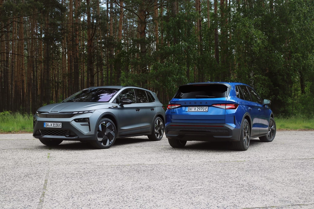 Skoda Elroq RS to najszybszy kompakt producenta w historii. Dwa nowoczesne samochody elektryczne stojące obok siebie na betonowym placu, w tle widoczny gęsty lasek sosnowy.