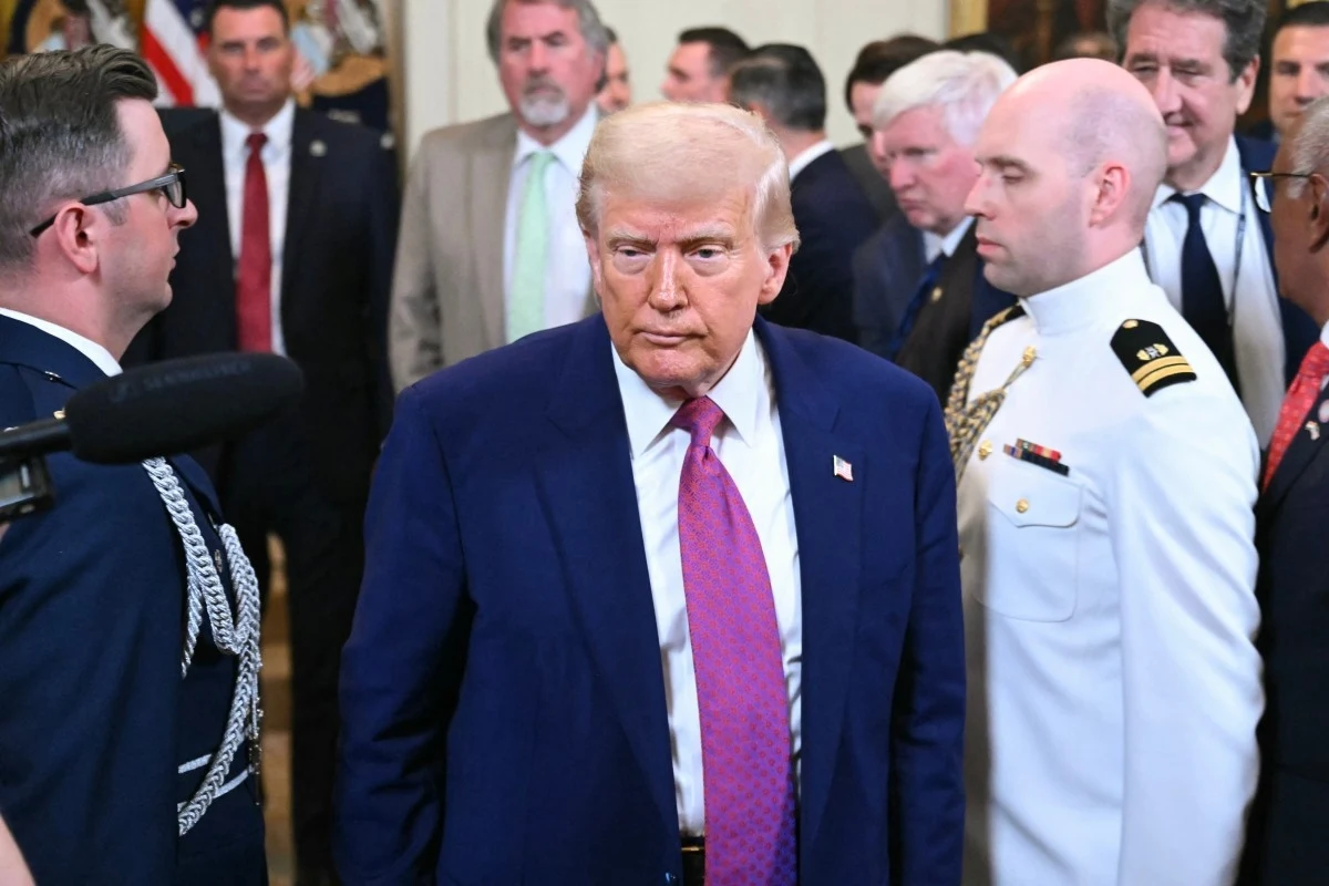 Polityka Donalda Trumpa prowadzi do eskalacji zarówno w Ukrainie, jak i na Bliskim Wschodzi i w relacjach z Chinami - pisze "NYT" Mężczyzna w garniturze i różowym krawacie przechodzi przez tłum osób, wokół niego znajdują się ludzie w mundurach oraz stroju formalnym, scena odbywa się w eleganckim wnętrzu.