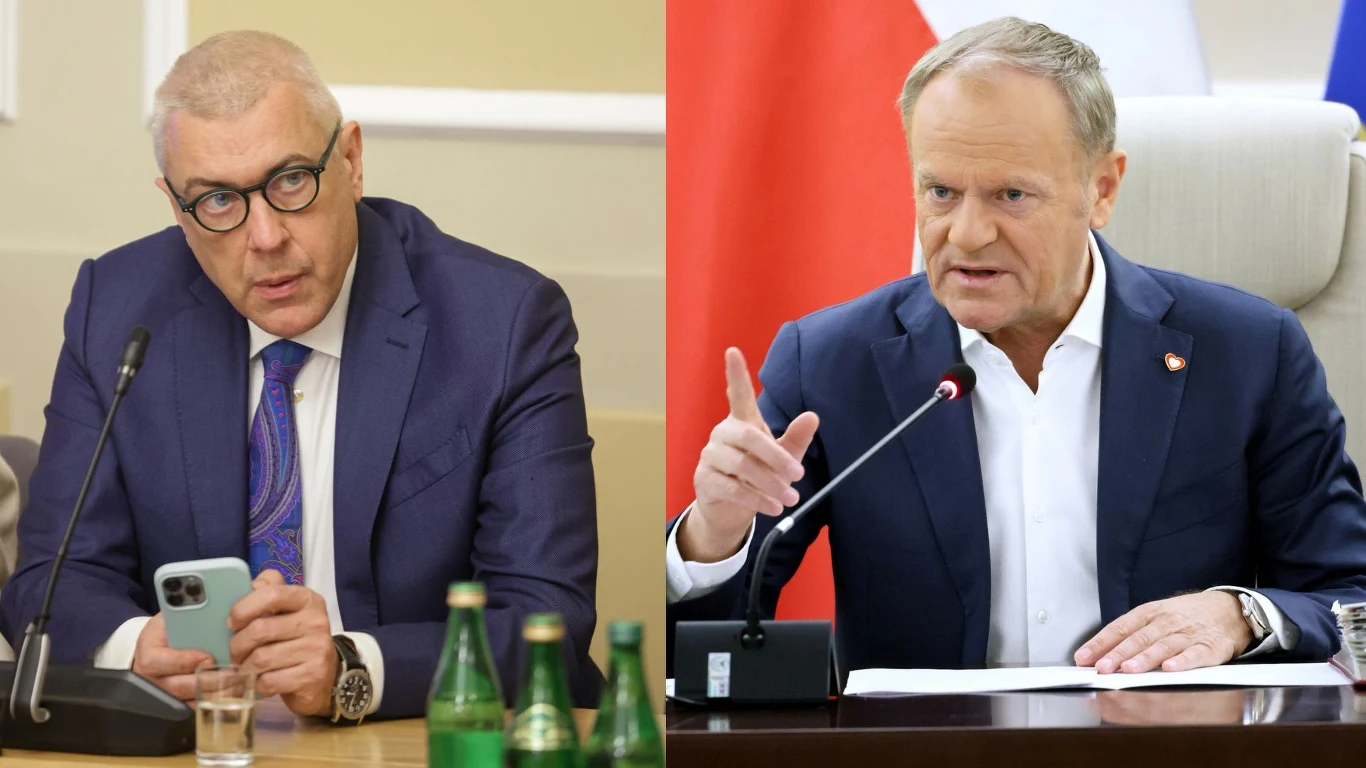 Wyciekła z rozmowa Romana Giertycha z Donaldem Tuskiem Dwóch mężczyzn w garniturach siedzących przy stole konferencyjnym, jeden trzyma smartfon i notatki, na stole stoją butelki z wodą, drugi gestykuluje dłonią podczas wypowiedzi, obok znajduje się mikrofon, w tle fragment flagi.