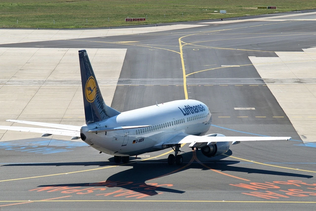 Samolot Lufthansy został zawrócony z powodu nagłego zgłoszenia Samolot pasażerski linii Lufthansa kołujący po pasie startowym na lotnisku, widoczne oznakowanie pasa i fragment zielonej trawy w tle.
