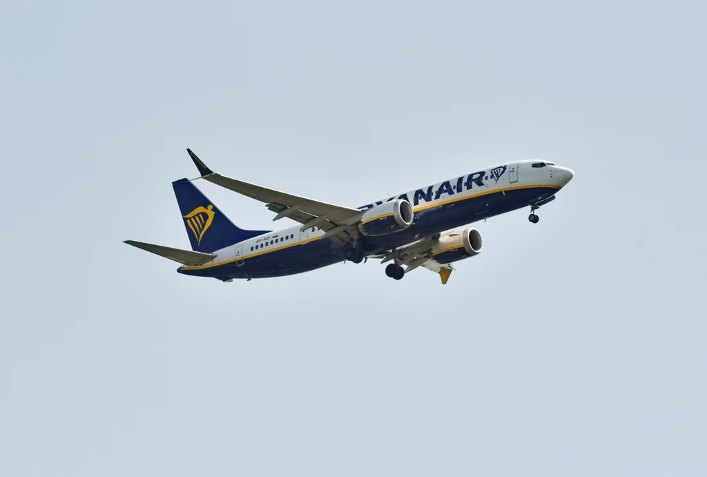 Najtańsze bilety lotnicze z Polski do Zadaru w obie strony kosztują około 350 zł. Samolot pasażerski linii Ryanair w locie na tle jasnego nieba, widoczne logo i charakterystyczne barwy firmy.