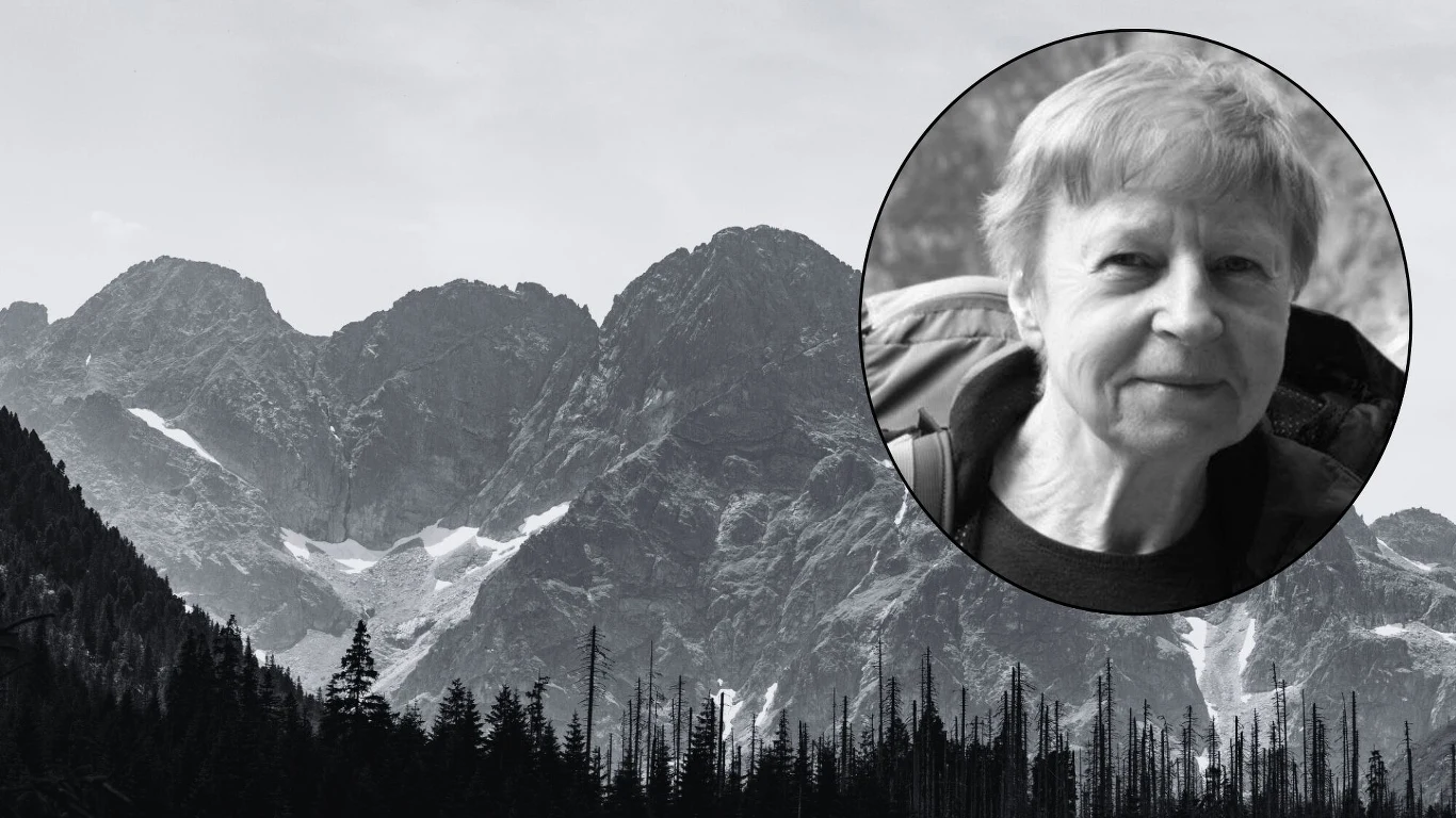 Zginęła polska himalaistka Krystyna Palmowska Portret starszej kobiety w czerni i bieli w okrągłym kadrze na tle górskich szczytów i lasu iglastego, zdjęcie w odcieniach szarości.