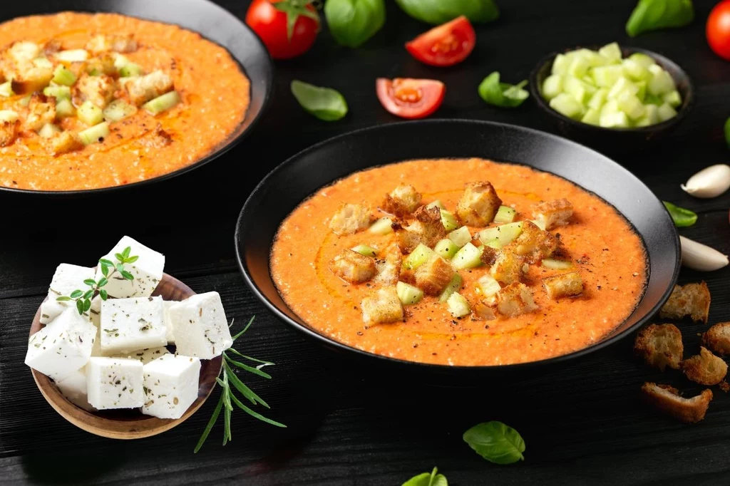 Gazpacho możesz podać z grzankami lub opiekanym chlebem oraz fetą, kozim serem lub halloumi Miski z kremową zupą z pomidorów udekorowaną grzankami i kawałkami świeżego ogórka, w otoczeniu świeżych ziół, pomidorów, czosnku oraz kawałków białego sera na osobnym talerzyku.