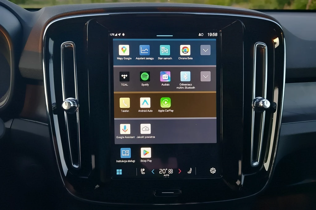 System infotainment Volvo EX40 oparty jest na Android Automotive Panel multimedialny samochodu z włączonym wyświetlaczem dotykowym, na którym widoczne są różne aplikacje, w tym Spotify, Tidal, Google Assistant, Android Auto i Apple CarPlay; poniżej pasek ustawień klimatyzacji.