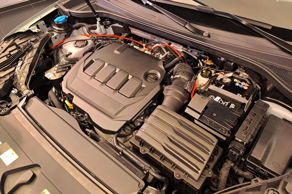 Audi Q3 będzie dostępne z silnikami benzynowymi, jako hybryda plug-in, a także z jednostką wysokoprężną. Podstawową odmianę napędową będzie stanowić 150-konna miękka hybryda. Nowoczesny silnik samochodowy z widocznymi elementami osprzętu, takimi jak akumulator, filtry, przewody i plastikowa osłona silnika, ukazujący schludnie zorganizowaną komorę silnika.