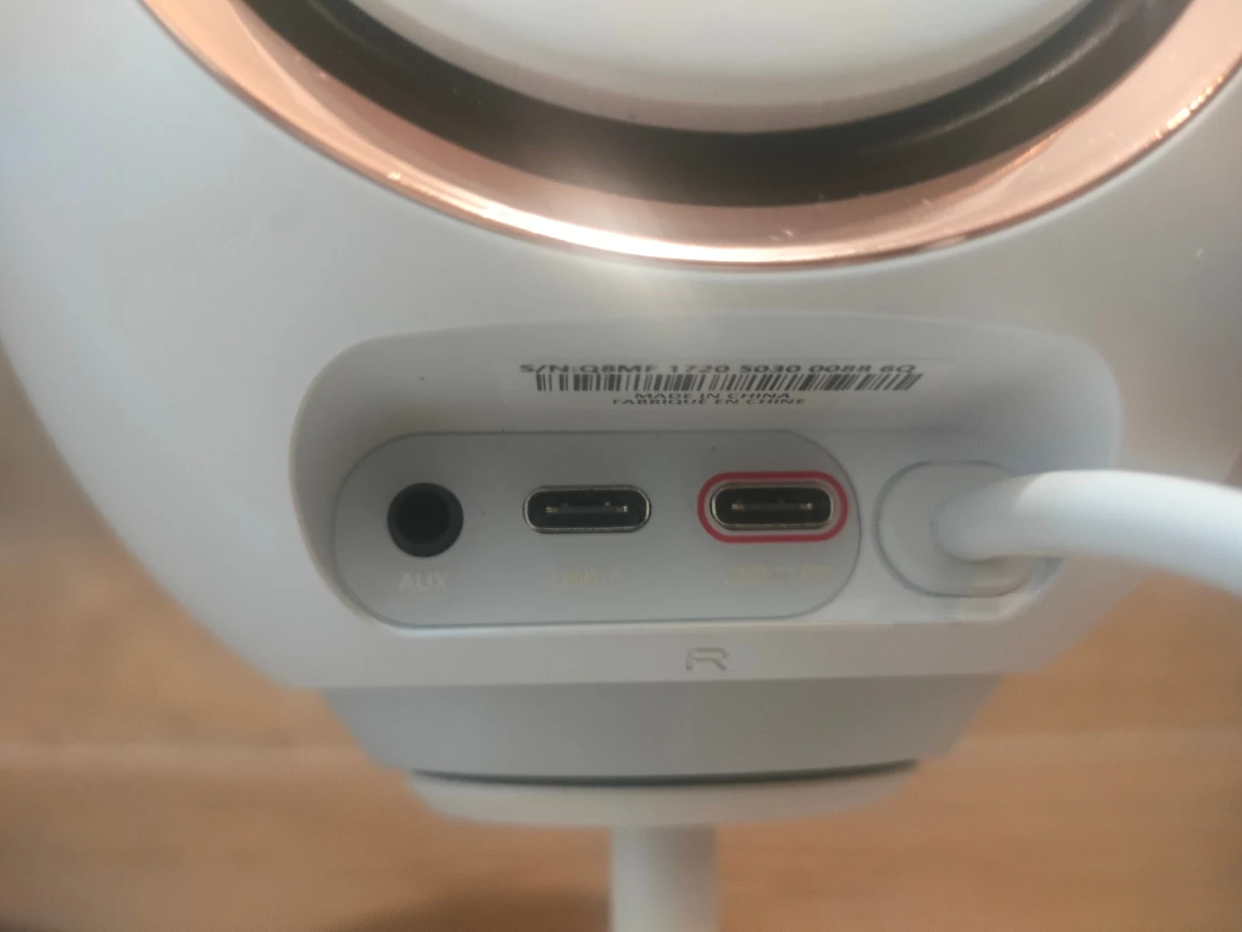 Panel złączy w urządzeniu elektronicznym, widoczne wejścia AUX, USB-C oraz drugie złącze USB-C z podłączonym kablem, wykończenia w kolorze białym z detale w kolorze miedzianym.