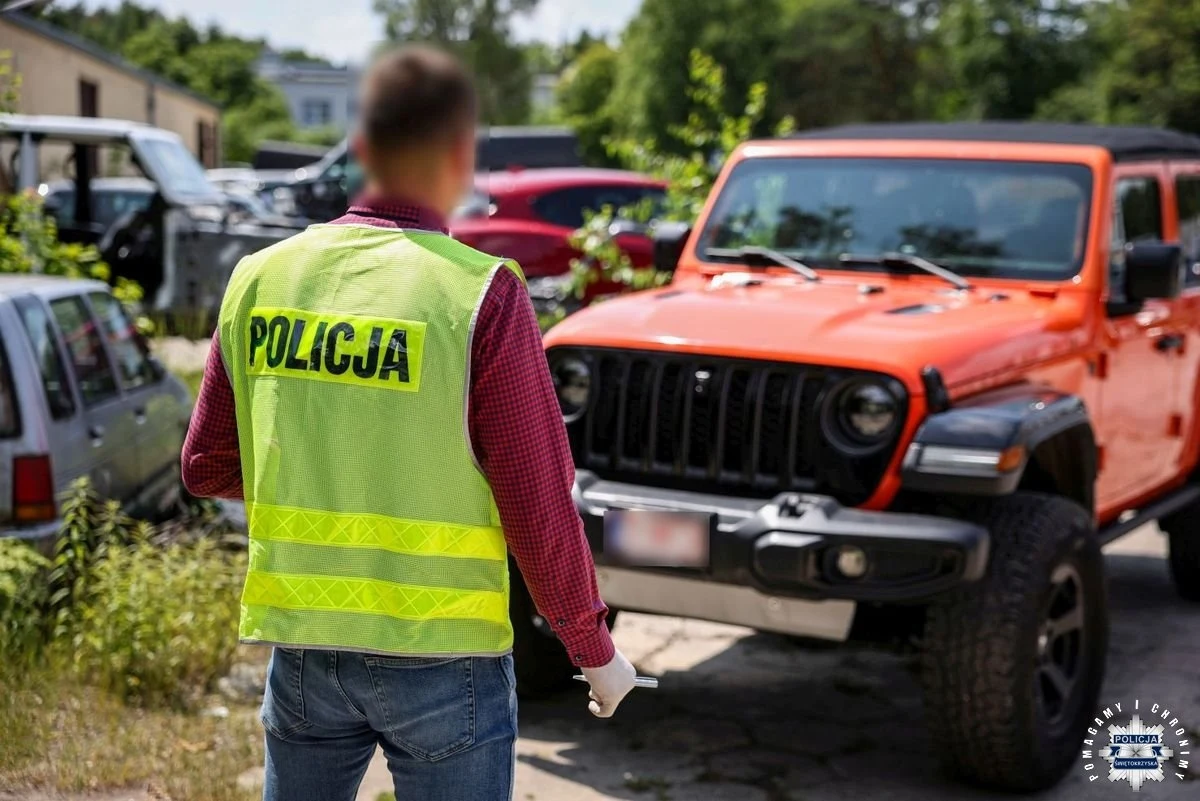 Po nitce do kłębka - od skradzionego Jeepa na terenie Śląska do rozbicia zorganizowanej grupy przestępczej. Policjant w kamizelce odblaskowej ogląda pomarańczowego jeepa zaparkowanego na parkingu, wokół widoczne są inne samochody, otoczenie wskazuje na teren zewnętrzny przy zabudowaniach.