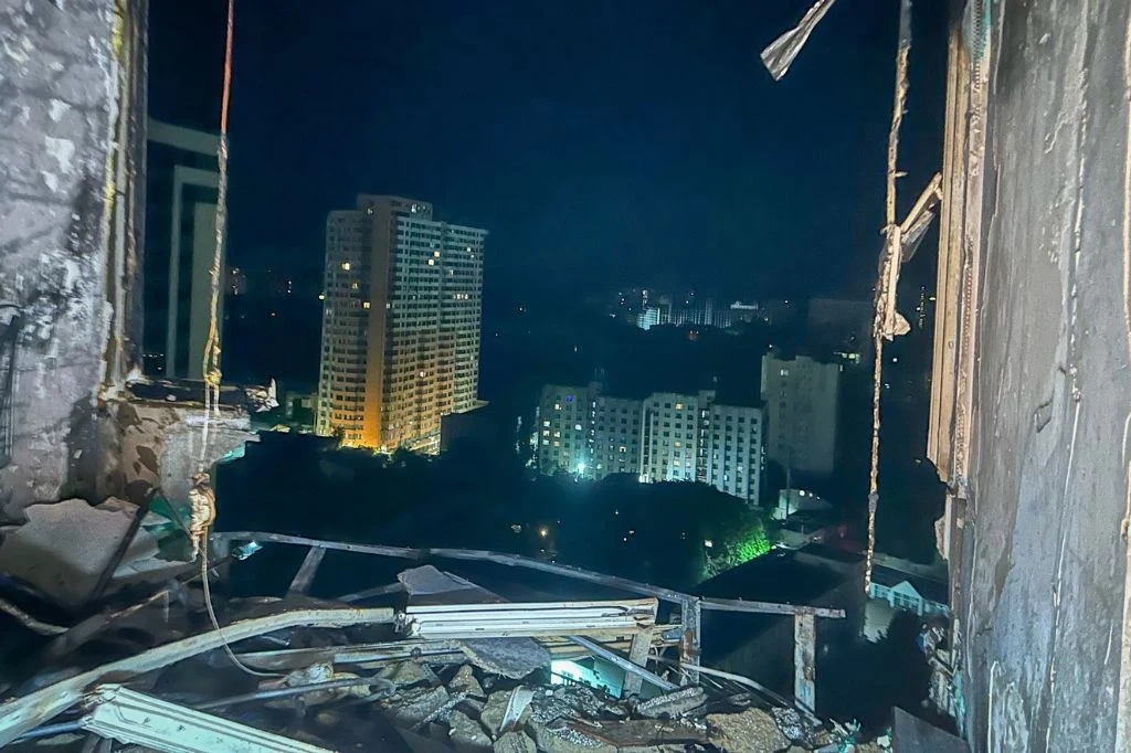 Rosjanie zaatakowali Odessę i Charków (na zdj.). Celem stały się obiekty cywilne, są ranni Panorama miasta nocą widziana przez zniszczone okno budynku, w kadrze widoczne gruzy i uszkodzone ściany oraz oświetlone wieżowce na dalszym planie.