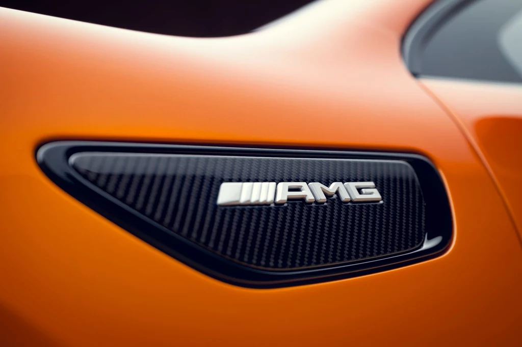 Concept AMG GT XX zapowiada pierwszy seryjnie produkowany samochód zbudowany na platformie AMG.EA. Logo AMG na bocznym elemencie pomarańczowego samochodu sportowego, detal wykonany z włókna węglowego oraz metalicznym napisem.