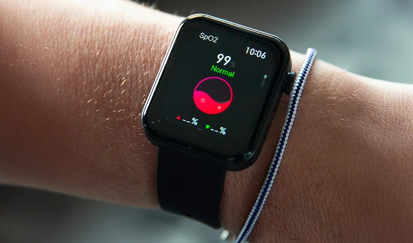 Aby żyć lepiej, nie trzeba rewolucji – wystarczy mały impuls i drobna zmiana Smartwatch na nadgarstku wyświetlający poziom saturacji tlenu we krwi (SpO2) z wynikiem 99%, pasek zegarka ma kolor czarny, obok opaska materiałowa w biało-niebieskie paski.