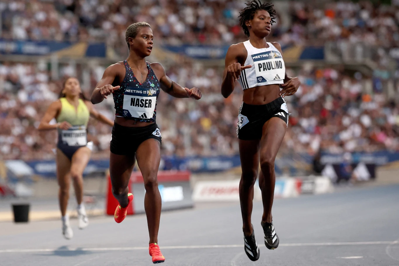 Salwa Eid Naser i Marileidy Paulino Dwie zawodniczki biegną niemal równolegle na bieżni stadionu lekkoatletycznego podczas zawodów, obie skoncentrowane na finiszu, tłum kibiców rozmyty w tle.