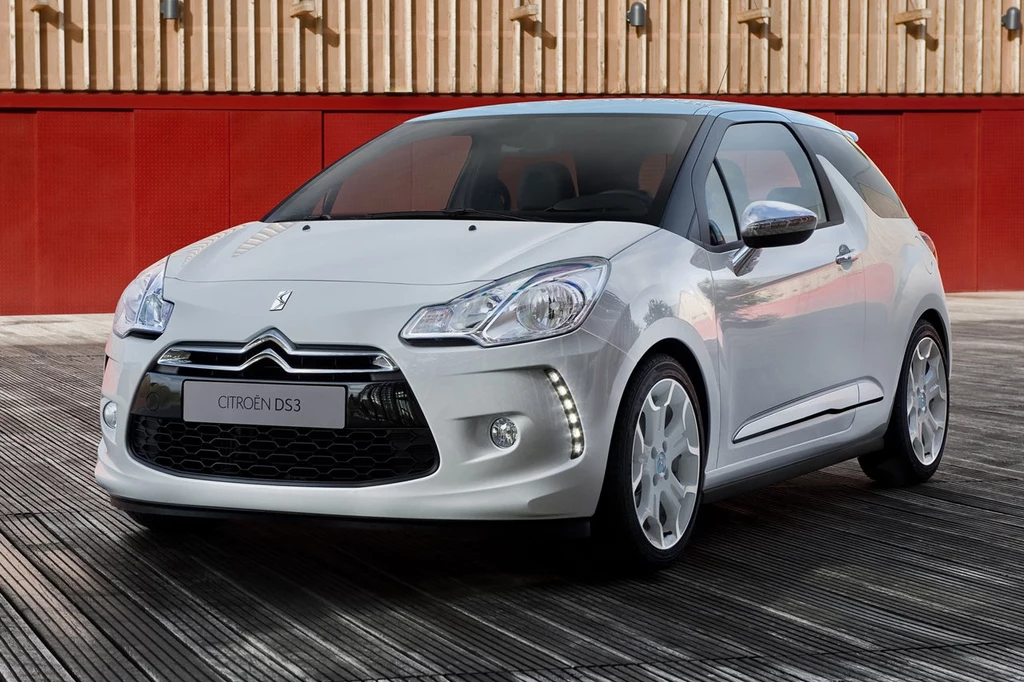 Problem z poduszkami Takaty dotycz także Citroena DS3, przemianowanego potem na DS 3 Biały samochód Citroën DS3 zaparkowany na drewnianej nawierzchni, w tle elewacja w ciepłych odcieniach z czerwonymi panelami, nowoczesny i elegancki wygląd pojazdu podkreślony przeszklonymi reflektorami i światłami LED.