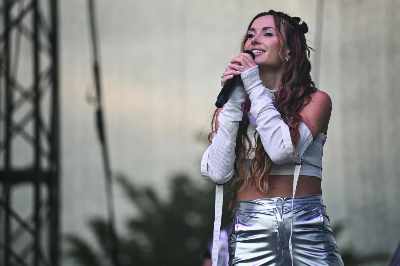 Wersow została skrytykowana przez fanów Młoda kobieta w metalicznej, srebrnej stylizacji śpiewa na scenie trzymając mikrofon, wokół widoczna stalowa konstrukcja sceniczna oraz rozmyte tło.