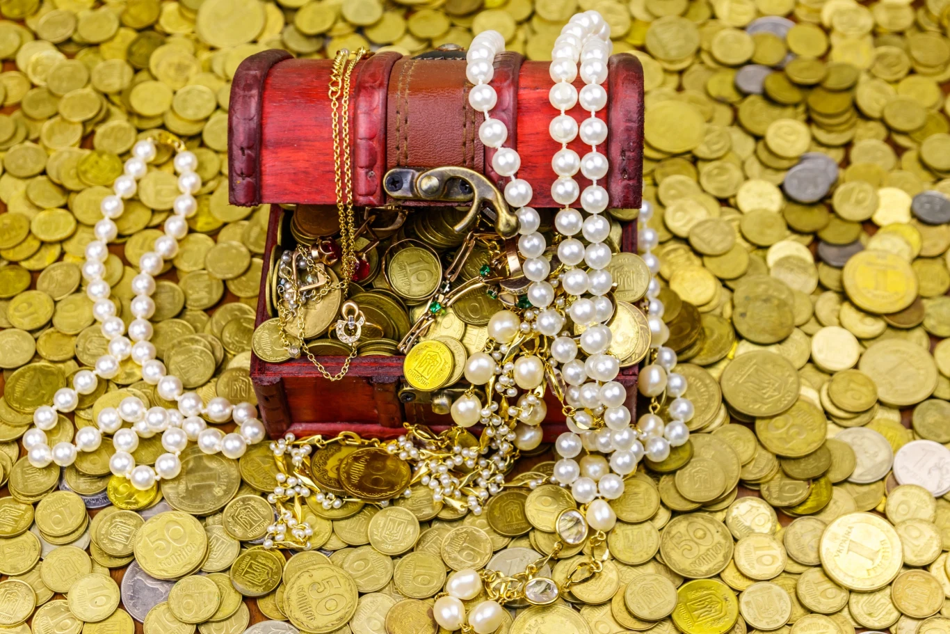 Ludwik Sobolewski: Ciekawie zrobiło się na rynku dóbr luksusowych Drewniana skrzynia wypełniona złotymi monetami, sznurami pereł i biżuterią znajduje się na dużej ilości rozrzuconych monet.