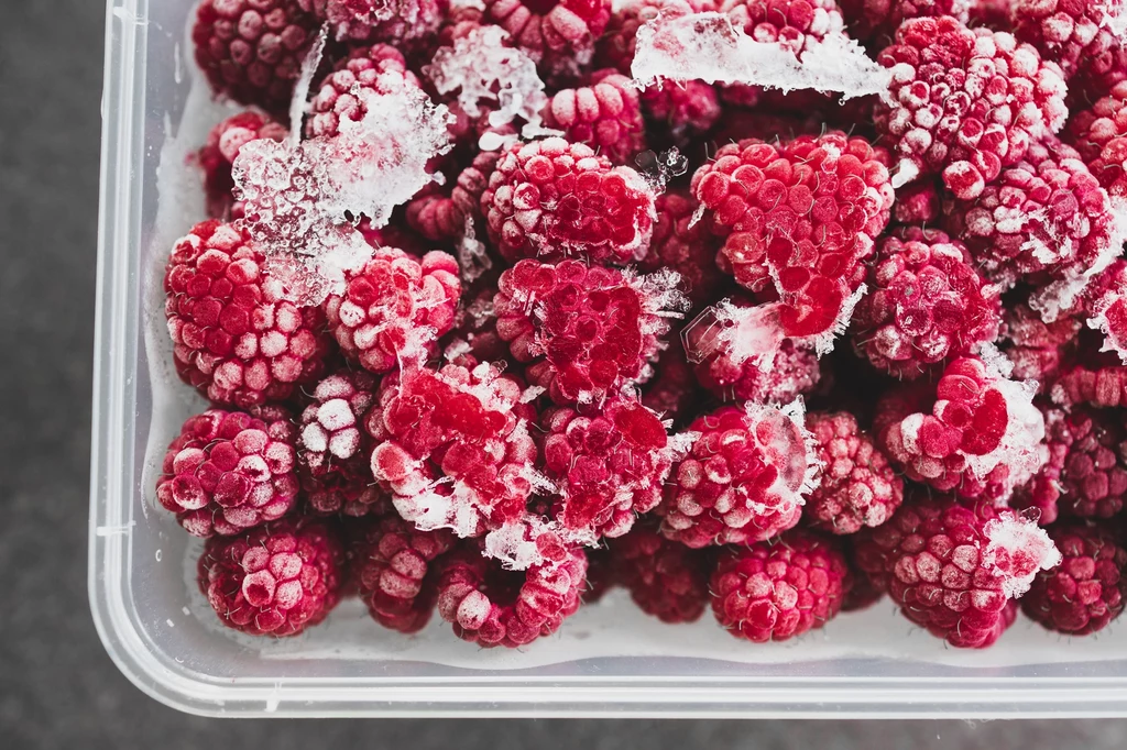 Niektóre delikatne owoce, jak maliny, po rozmrożeniu i tak przeistoczą się w mus. Im gorzej będą osuszone, tym większa "papka" powstanie Mrożone maliny ułożone w pojemniku, pokryte cienką warstwą szronu podkreślającą ich świeżość i teksturę.