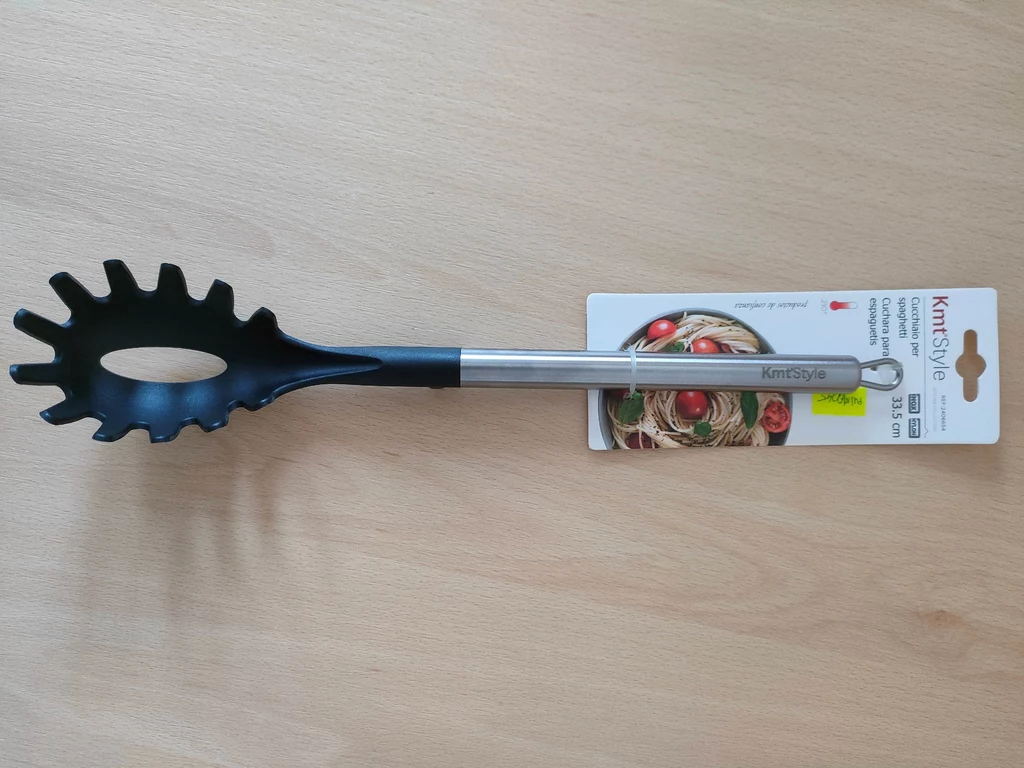 Łyżka do spaghetti zawiera groźne substancje - ostrzega GIS Łyżka do makaronu z czarną główką z tworzywa sztucznego i metalowym uchwytem, opakowanie producenta z widocznym oznaczeniem marki i ilustracją makaronu.