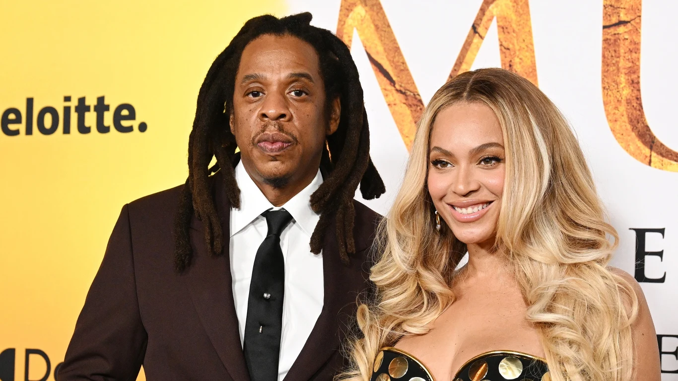 Jay - Z i Beyonce wystąpili razem podczas koncertu w Paryżu Para elegancko ubranych osób pozuje razem na tle żółtej ścianki z widocznymi elementami tekstu i logo.