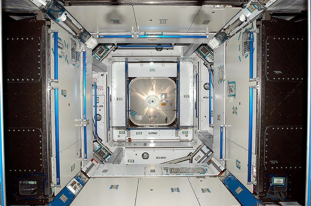 Wnętrze modułu Harmony w 2007 roku Wnętrze modułu stacji kosmicznej z widocznym centralnym włazem, otoczone panelami i urządzeniami technicznymi, oznaczeniami oraz instalacjami służącymi do utrzymania i obsługi infrastruktury kosmicznej.
