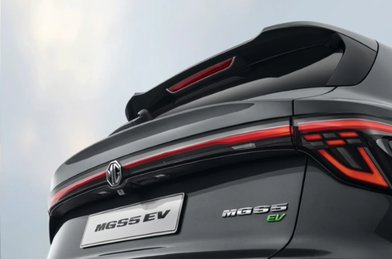 Tylna część samochodu MG5 EV z widocznymi nowoczesnymi lampami LED, logotypem marki i oznaczeniem modelu, w kolorze grafitowym, z widocznym fragmentem spoilera.