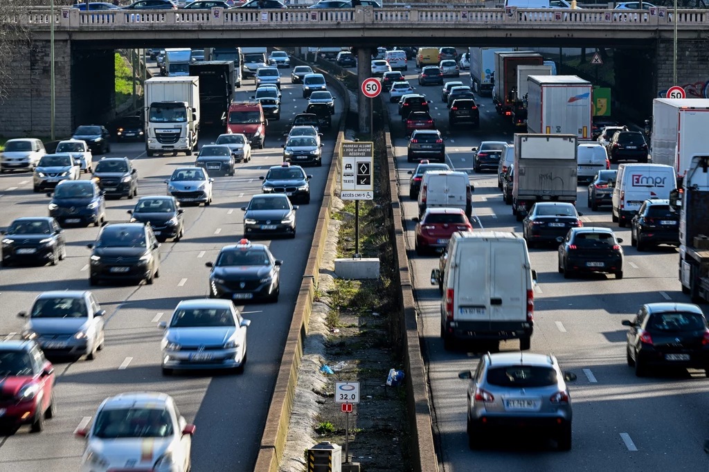 Francja wydawała zakaz jazdy (Stop Drive) dla 1,7 mln samochodów używanych różnych marek, wyposażonych w wadliwe poduszki Gęsty ruch uliczny na wielopasmowej autostradzie z mostem nad jezdnią, liczne samochody osobowe i ciężarowe poruszają się w obu kierunkach, na środku bariery ochronne i znaki drogowe.