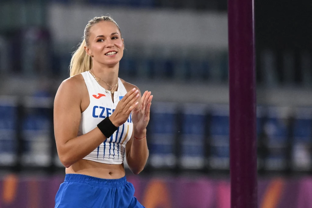 Amalie Svabikova Uśmiechnięta kobieta w stroju sportowym z napisem 'CZE' na koszulce, bijąca brawo, znajduje się na stadionie lekkoatletycznym; w tle widoczne trybuny.