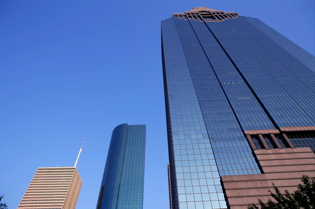 Houston jest miastem USA, które szybko się zapada Wysokie, nowoczesne wieżowce z elewacją ze szkła i stali odbijające błękitne niebo, budynki ustawione obok siebie tworzą panoramę miejską.