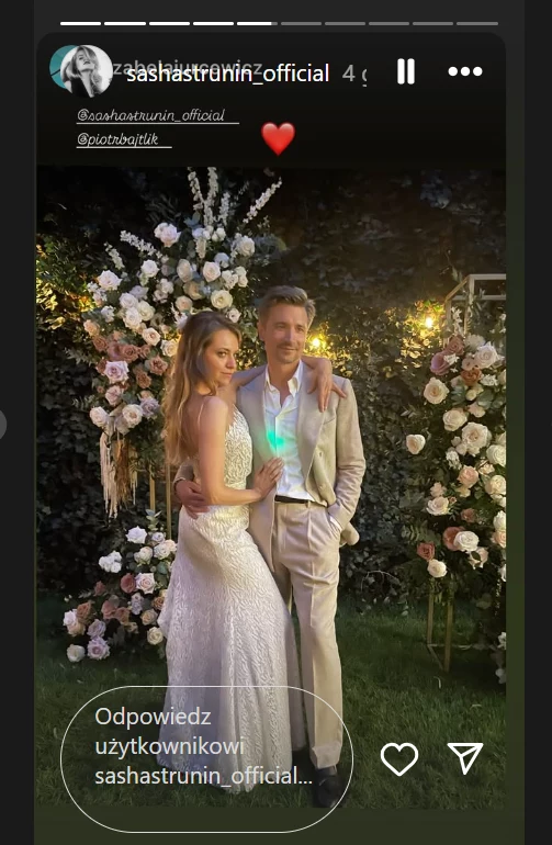 Sasha Strunin na relacji na Instagramie opublikowała kilka zdjęć i nagrań ze ślubu z Piotrem Bajtlikiem Para ubrana elegancko, kobieta w białej sukni i mężczyzna w jasnym garniturze, pozują razem na tle efektownej kwiatowej dekoracji i wieczornego oświetlenia.