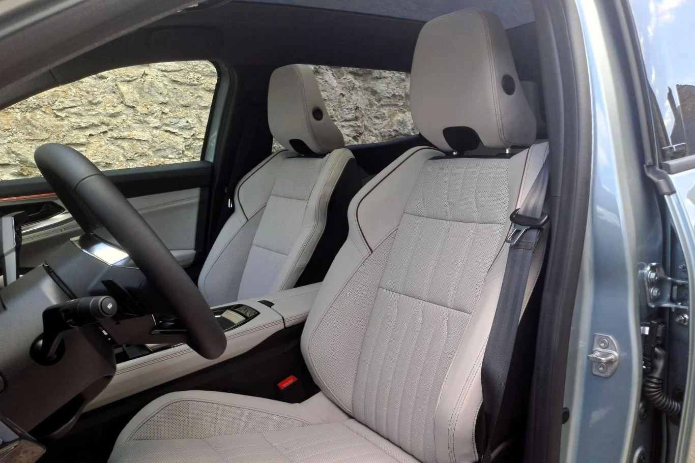 Wnętrze nowoczesnego samochodu z luksusowymi, jasnymi skórzanymi fotelami, elegancką deską rozdzielczą i dużą ilością miejsca dla kierowcy oraz pasażera.