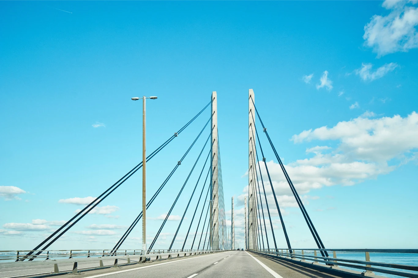 1 lipca most obchodzi 25-lecie. Ceny ponownie wzrosną. Nowoczesny most wantowy nad wodą, niebieskie niebo z kilkoma chmurami, pusta jezdnia prowadząca przez konstrukcję stalowych lin i wysokich słupów.