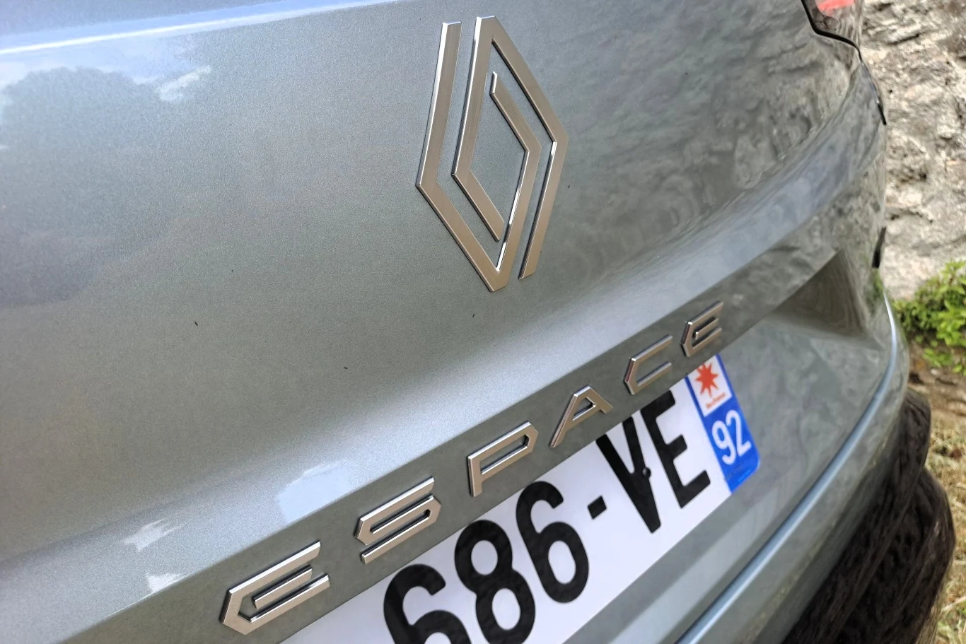 Logo Renault, napis 'ESPACE' oraz fragment francuskiej tablicy rejestracyjnej na srebrnym nadwoziu samochodu.