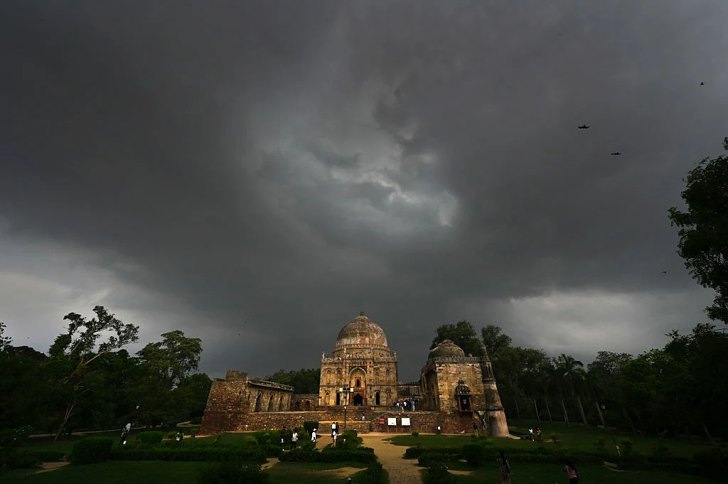 Monsun w Indiach pojawił się wcześniej niż zwykle. Swoim zasięgiem objął cały kraj. W miejscowości Shimla ulewne deszcze doprowadziły do zawalenia się pięciopiętrowego budynku Historyczna budowla otoczona zielenią pod ciemnym, burzowym niebem, z nielicznymi sylwetkami osób spacerujących po ogrodzie.