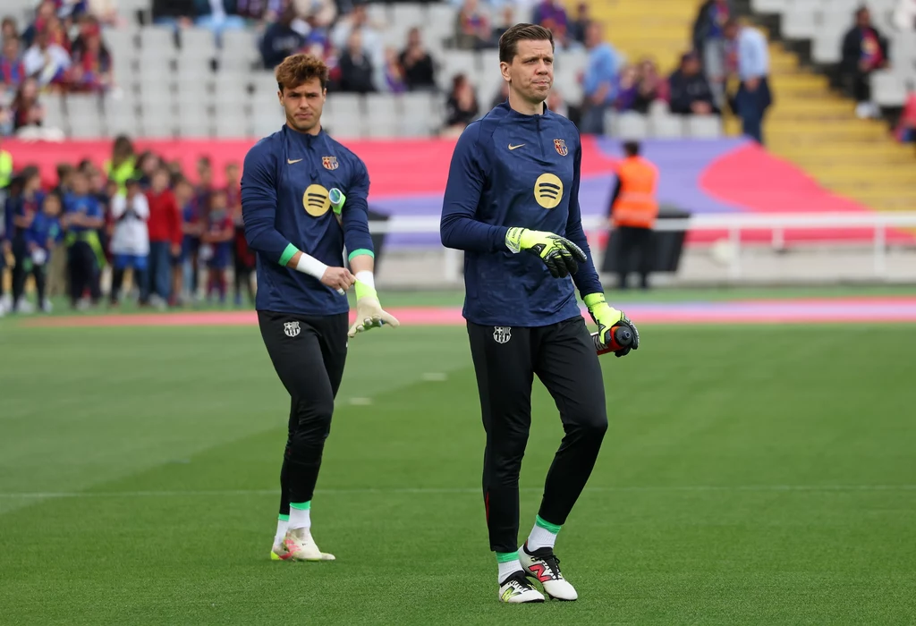 Wojciech Szczęsny i Diego Kochen Dwóch bramkarzy w strojach treningowych jednej z europejskich drużyn piłkarskich stoi na murawie stadionu, za nimi widoczna trybuna z kibicami.