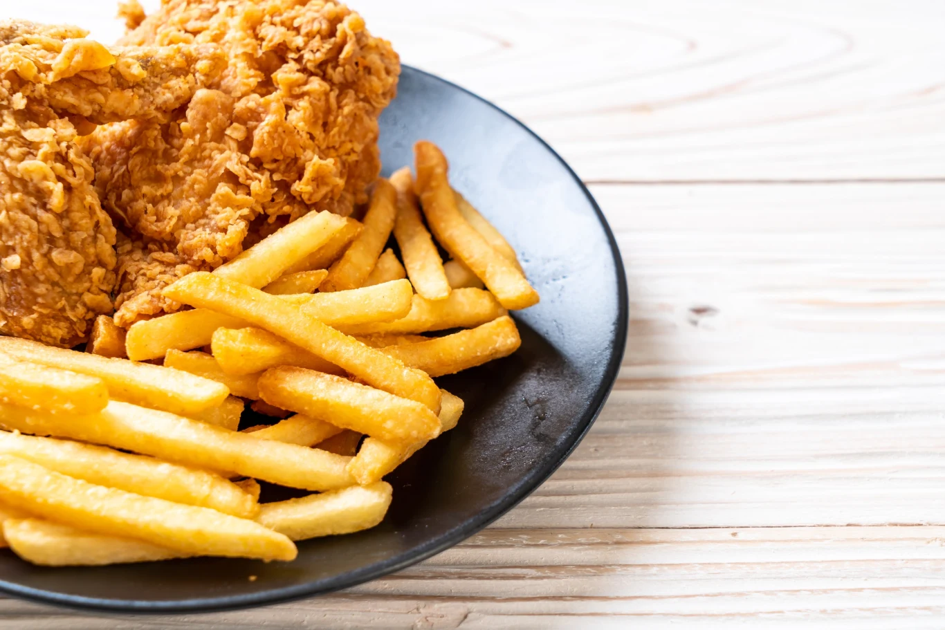 KFC w Danii zamyka do odwołania wszystkie swoje restauracje Chrupiące kawałki kurczaka w panierce obok porcji złocistych frytek na czarnym talerzu ustawionym na jasnym, drewnianym stole.