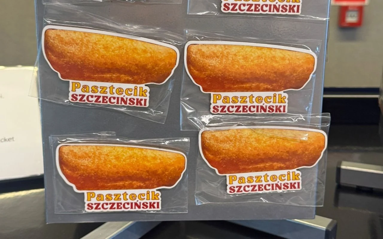 Naklejki przedstawiające pasztecika szczecińskiego, umieszczone na szarej planszy ekspozycyjnej, każda naklejka podpisana kolorowym napisem Pasztecik Szczeciński.