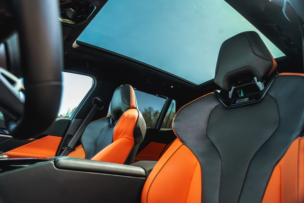 BMW M5 Touring Nowoczesne sportowe fotele samochodowe w czarno-pomarańczowym kolorze, duży panoramiczny dach szklany oraz elementy wnętrza samochodu wysokiej klasy.