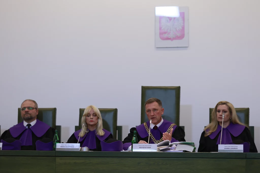 Posiedzenie Izby Kontroli Nadzwyczajnej i Spraw Publicznych w sprawie stwierdzenia ważności wyborów prezydenckich Czwórka sędziów ubranych w togi z fioletowymi akcentami siedzi za długim, zielonym stołem w sali sądowej, na ścianie za nimi widoczny jest herb Polski.