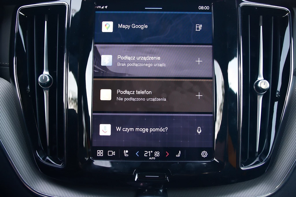 System pokładowy oparto na Android Automotive Ekran dotykowy systemu multimedialnego samochodu z widocznymi opcjami Mapy Google, podłączenia urządzenia, podłączenia telefonu oraz funkcją asystenta głosowego; wokół wyświetlacza elementy deski rozdzielczej.
