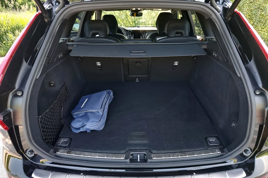 Pojemność bagażnika wersji plug-in wynosi 468 litrów Otwarty bagażnik samochodu osobowego typu SUV wyłożony czarną wykładziną, z zamontowaną siatką na drobiazgi z lewej strony i złożoną niebieską torbą na podłodze.