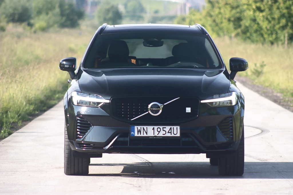 Volvo XC60 Polestar Enginereed Czarny samochód osobowy marki Volvo, model SUV, stoi na wiejskiej drodze otoczonej zielenią, w widoku na wprost. Tablica rejestracyjna widoczna na przednim zderzaku.