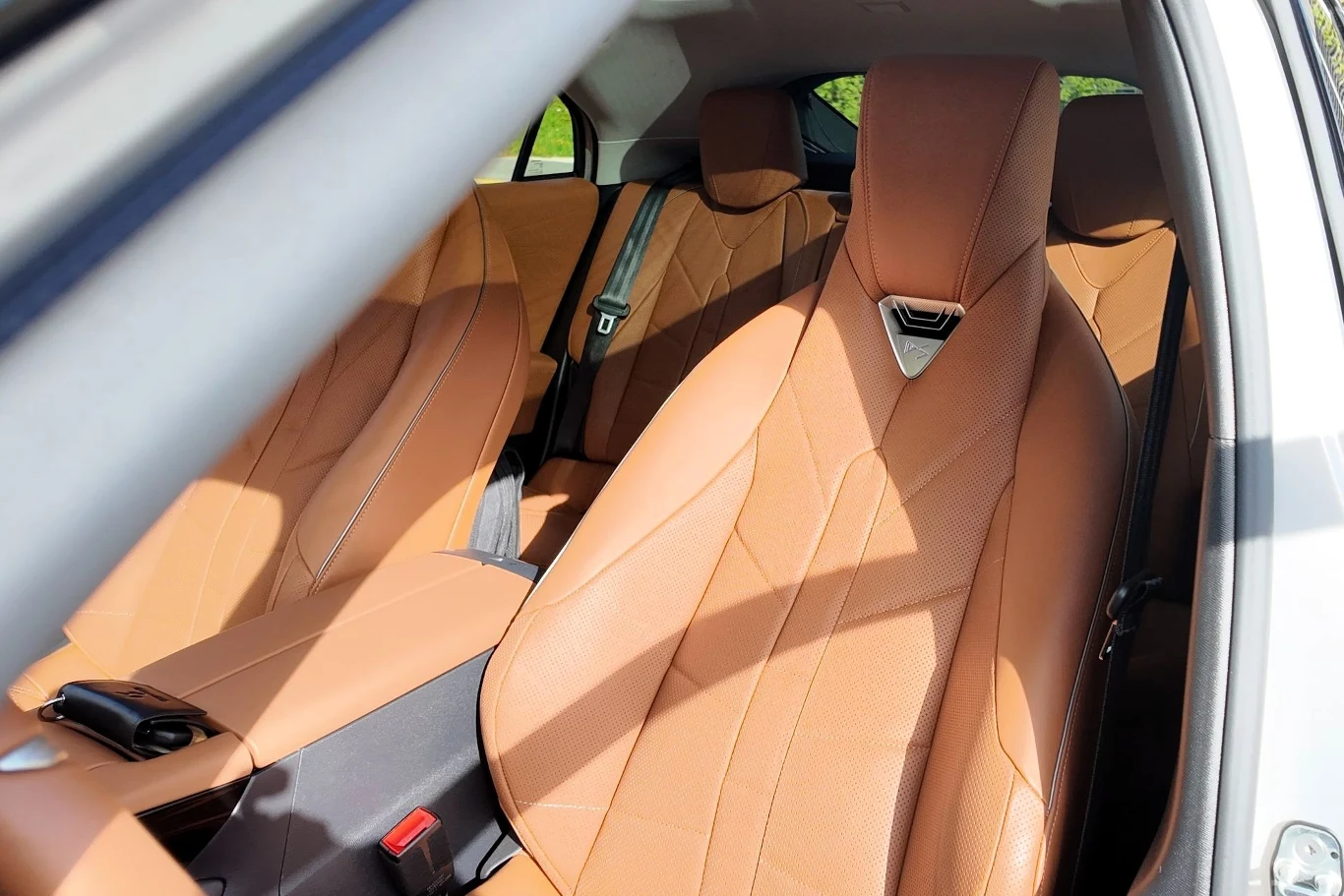 Luksusowe wnętrze samochodu z jasnobrązową skórzaną tapicerką na przednich i tylnych siedzeniach, eleganckim designem oraz widocznym pasem bezpieczeństwa.