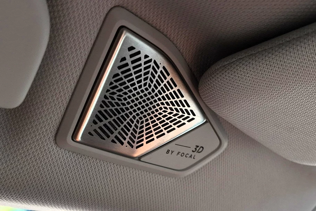 DS N8 może być wyposażone w 14-głośnikowy system audio opracowany wraz z firmą Focal. Nowoczesny, trójkątny głośnik samochodowy z metalową siatką o geometrycznym wzorze oraz napisem '3D by Focal', zamontowany na szarej tapicerce wnętrza pojazdu.