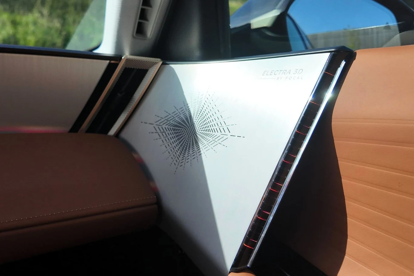 Wnętrze luksusowego samochodu z nowoczesną deską rozdzielczą, tapicerka w odcieniu brązu, dekoracyjny panel z geometrycznym wzorem i napisem 'ELECTRA XD'.