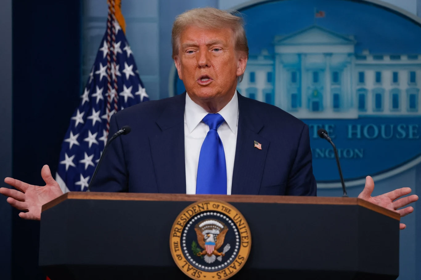 Administracja Donalda chce pozwać stację CNN Mężczyzna w ciemnym garniturze i niebieskim krawacie przemawia przy mównicy z pieczęcią prezydenta Stanów Zjednoczonych, w tle widoczne są flaga USA oraz tło z Białym Domem.